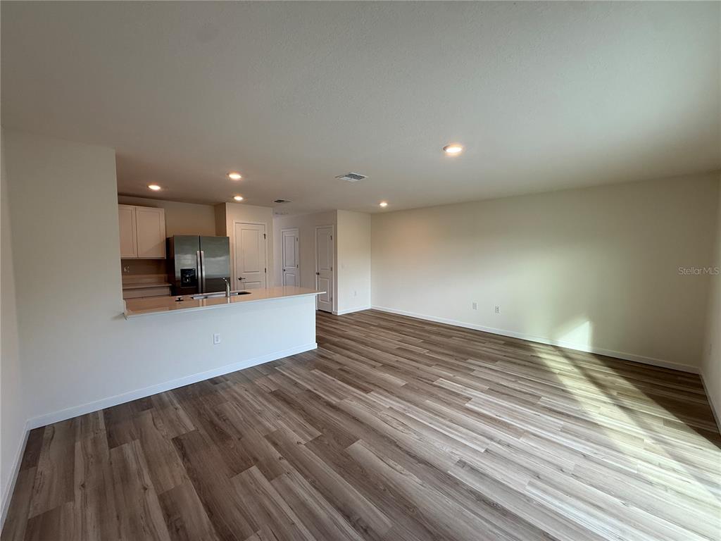 An open-concept living area features wood-look flooring and a kitchen with a breakfast bar — 6524 SW 82ND LOOP, OCALA, FL