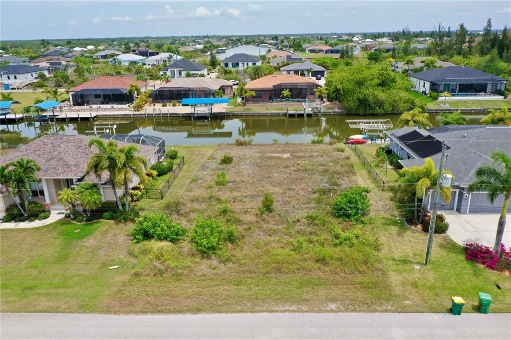 An aerial view shows a vacant waterfront lot situated between two residential houses — 15124 TAURUS CIRCLE, PORT CHARLOTTE, FL