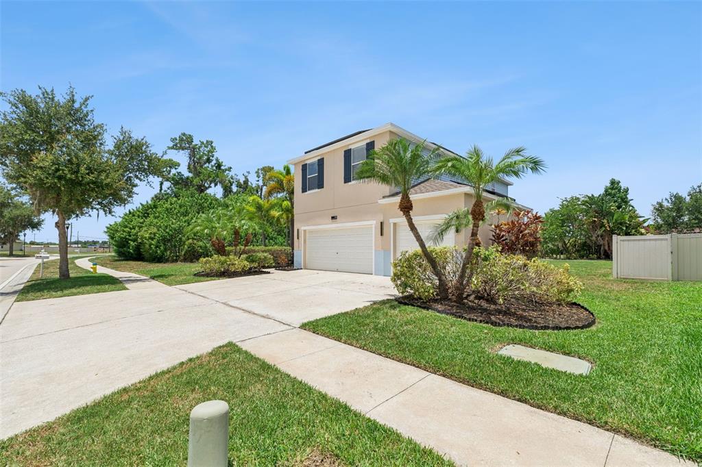A two-story house with a two-car garage, palm trees, and a concrete driveway — 112 SLIPPER KEY ROAD, APOLLO BEACH, FL