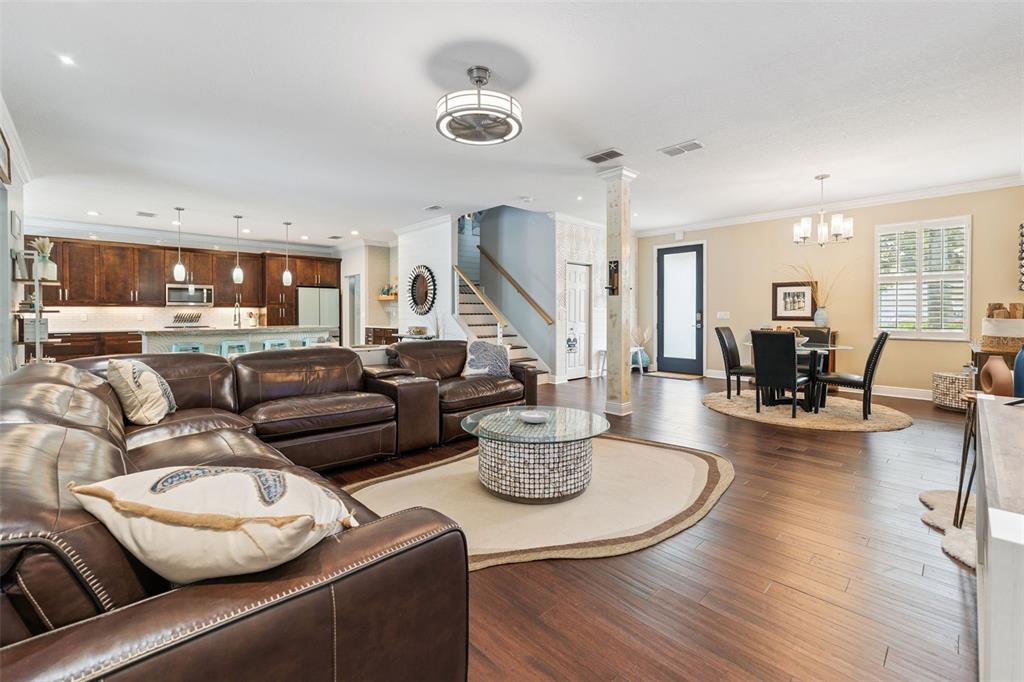 An open-concept living room features a leather sectional, dining area, and kitchen with dark cabinetry — 112 SLIPPER KEY ROAD, APOLLO BEACH, FL
