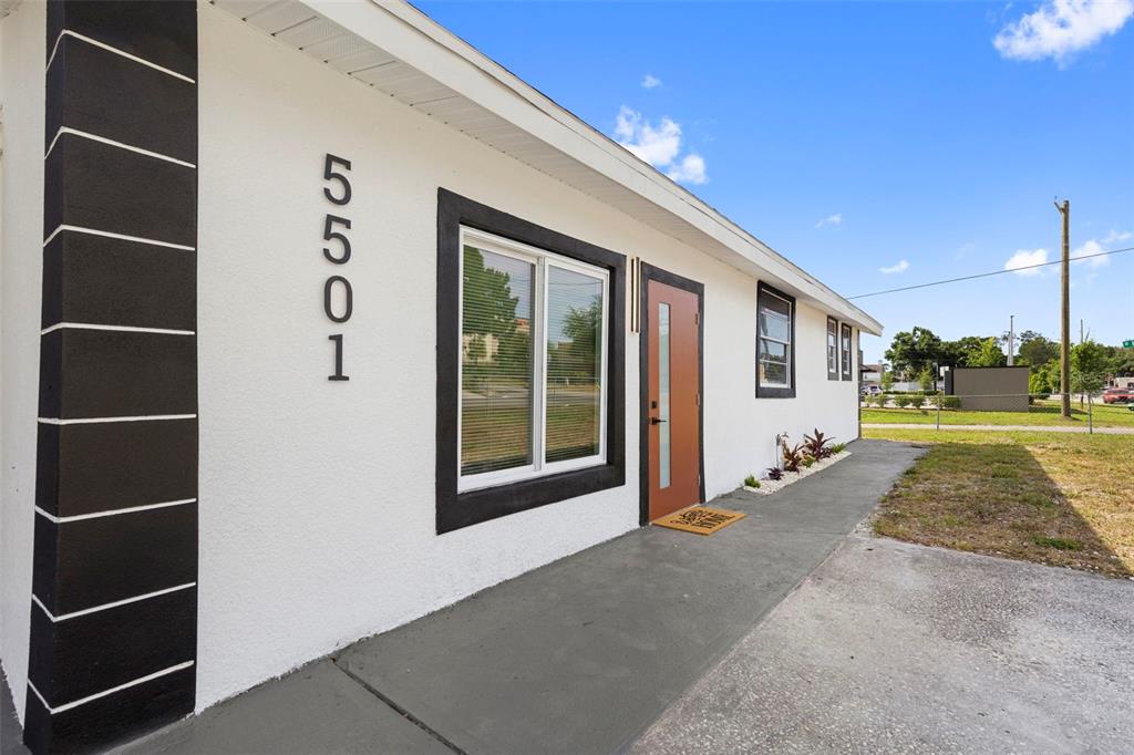The exterior of a white house features black trim, a brown door, and house numbers — 5501 N ALBANY AVENUE, TAMPA, FL