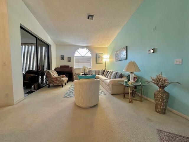A living room features a vaulted ceiling, a light blue accent wall, and beige carpeting — 5406 Firenze Drive # O, Boynton Beach FL 33437, BOYNTON BEACH, FL