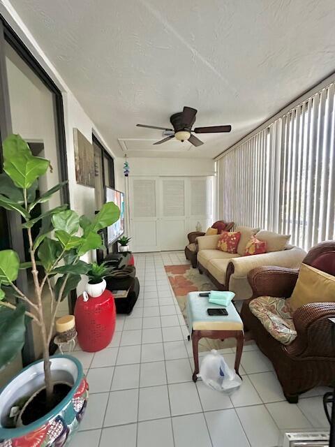 A sunroom features a ceiling fan, tiled floors, a sofa, and a wicker armchair — 5406 Firenze Drive # O, Boynton Beach FL 33437, BOYNTON BEACH, FL