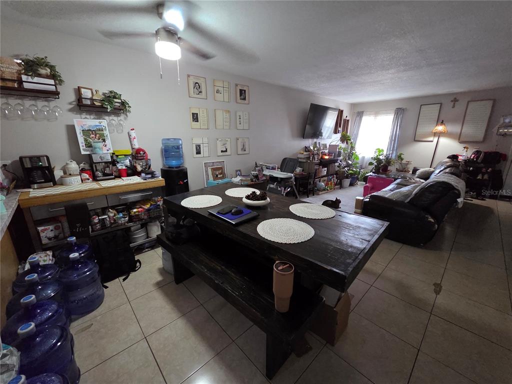 A dining area with a dark wooden table and benches sits adjacent to a living room — 4823 W MCELROY AVENUE UNIT D211, TAMPA, FL