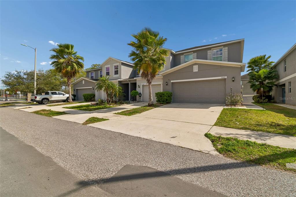 A two-story gray townhouse with a two-car garage and palm trees in the front yard — 10687 LAKE MONTAUK DRIVE, RIVERVIEW, FL