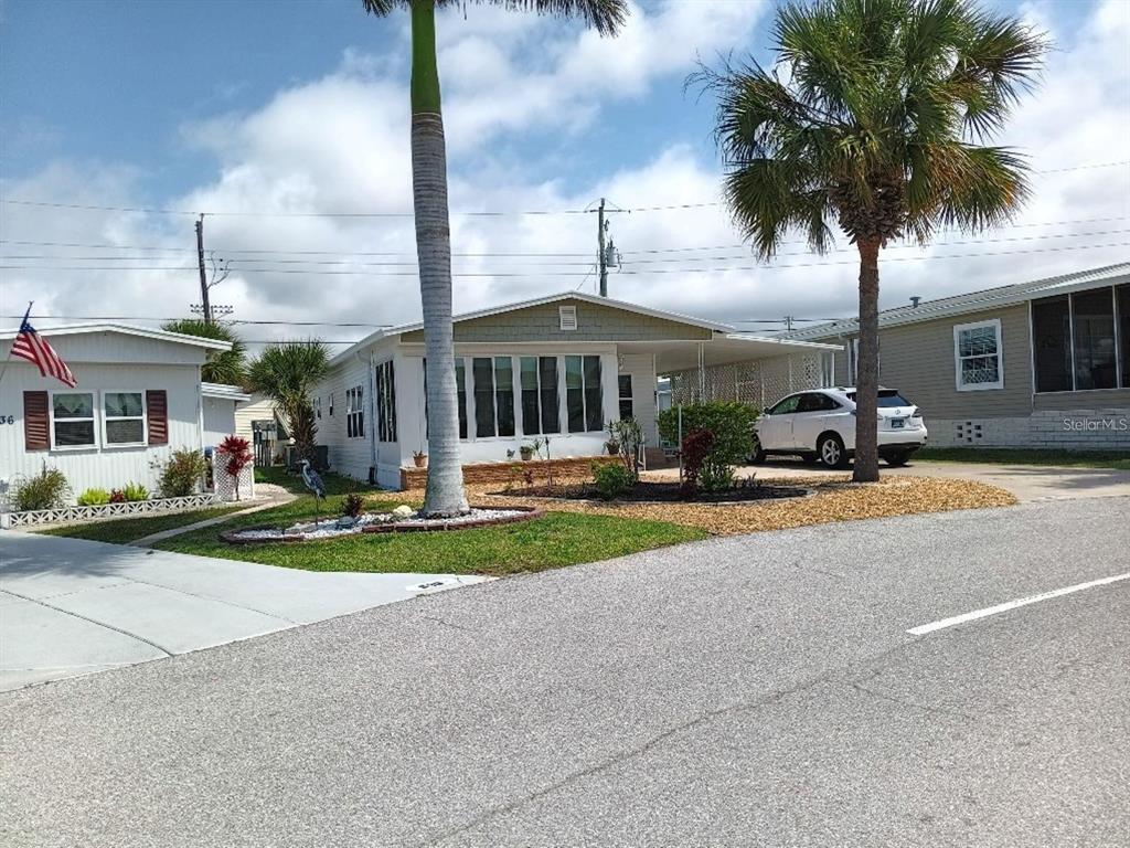 A street-level view of a manufactured home with a carport, palm trees, and landscaping — 638 LEISURE, VENICE, FL