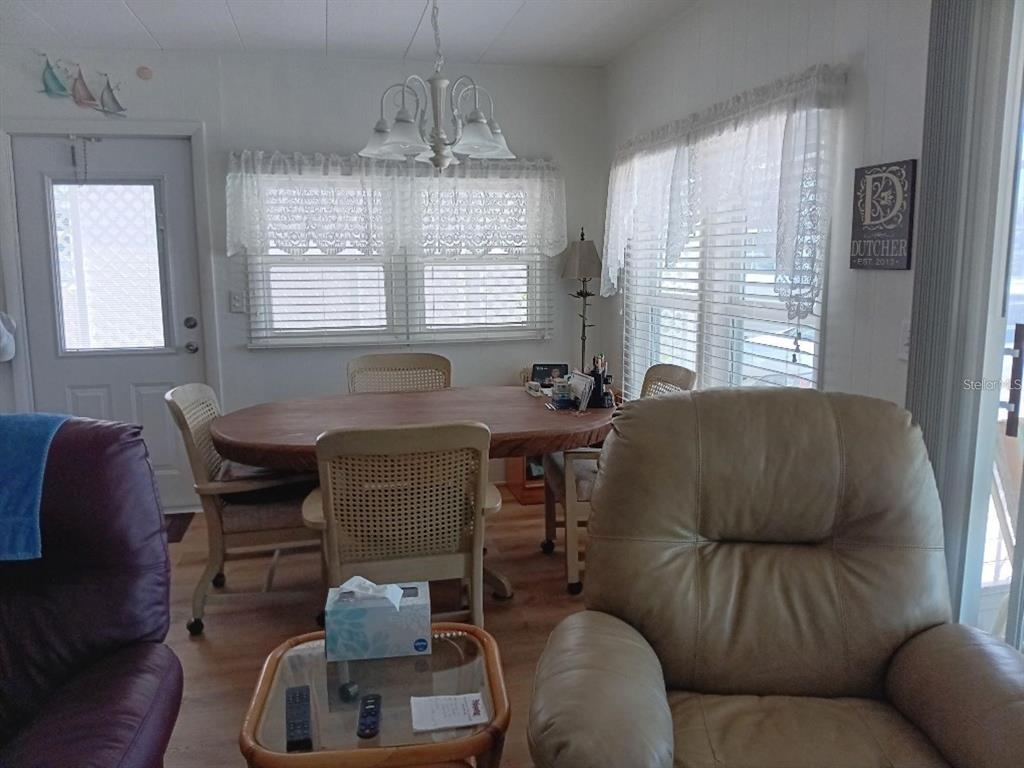 A dining area features a wooden oval table, four chairs, and a white chandelier — 638 LEISURE, VENICE, FL