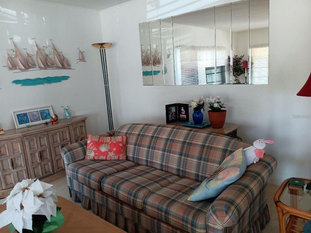 A living room features a plaid sofa, a mirrored wall, and a wooden sideboard — 638 LEISURE, VENICE, FL