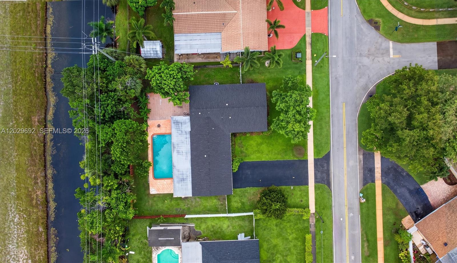 An aerial view shows a house with a black roof, a swimming pool, and driveway — 5501 Pine Ter, Plantation FL 33317, PLANTATION, FL