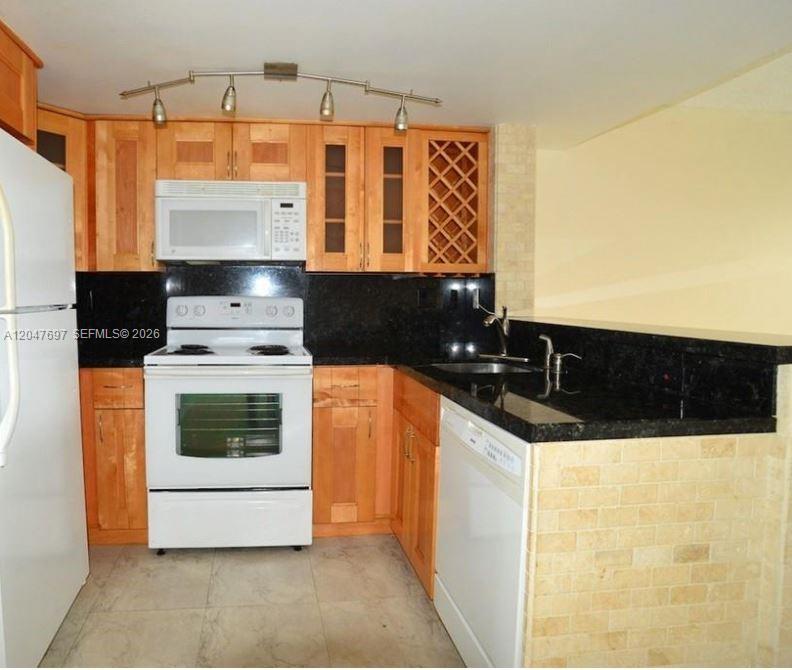 A kitchen features light wood cabinets, black countertops, white appliances, and a tiled breakfast bar — 510 NW 86th # 12, Miami FL 33126, MIAMI, FL