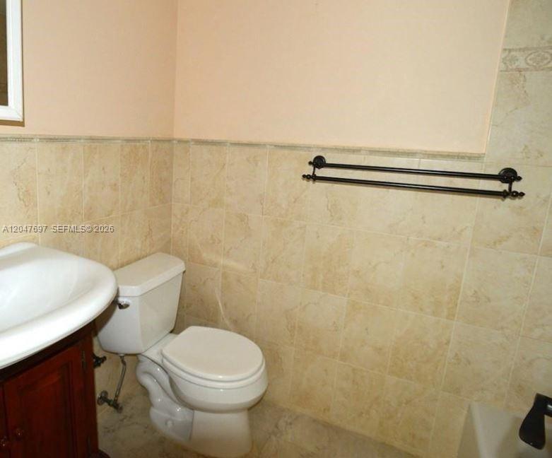 A bathroom features a white toilet, a pedestal sink, and a black double towel bar — 510 NW 86th # 12, Miami FL 33126, MIAMI, FL