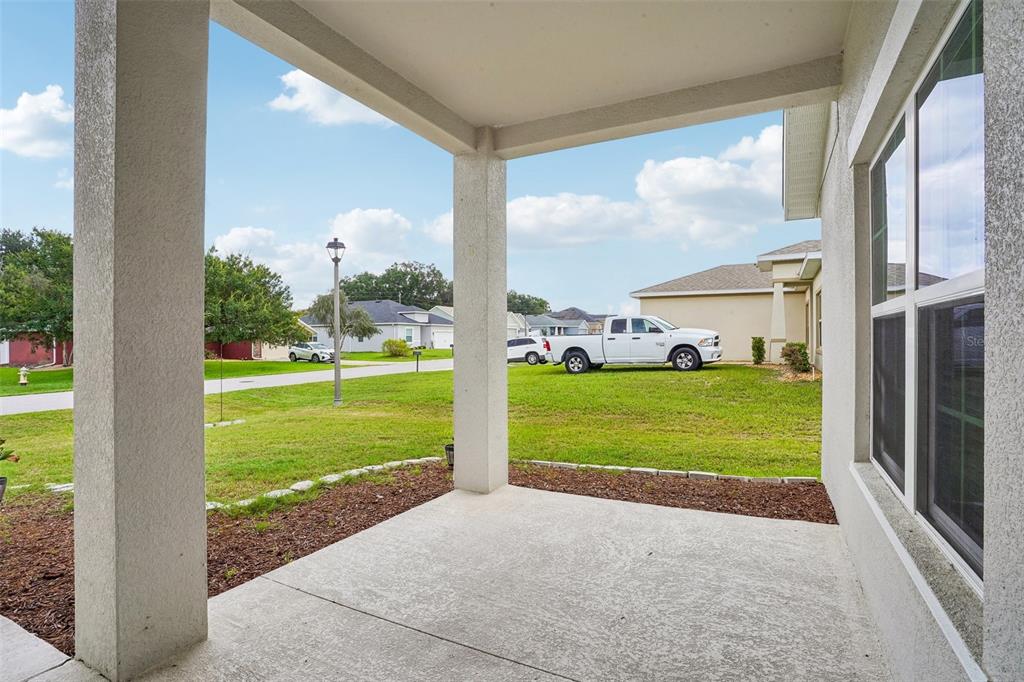 A covered concrete patio overlooks a suburban lawn with a white pickup truck parked nearby — 5494 SE 91ST STREET, OCALA, FL