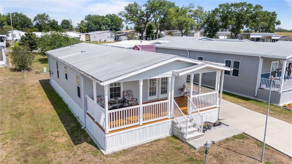 An elevated manufactured home features a white exterior, a front porch, and a concrete driveway — 10042 COLLINGWOOD AVENUE, DADE CITY, FL