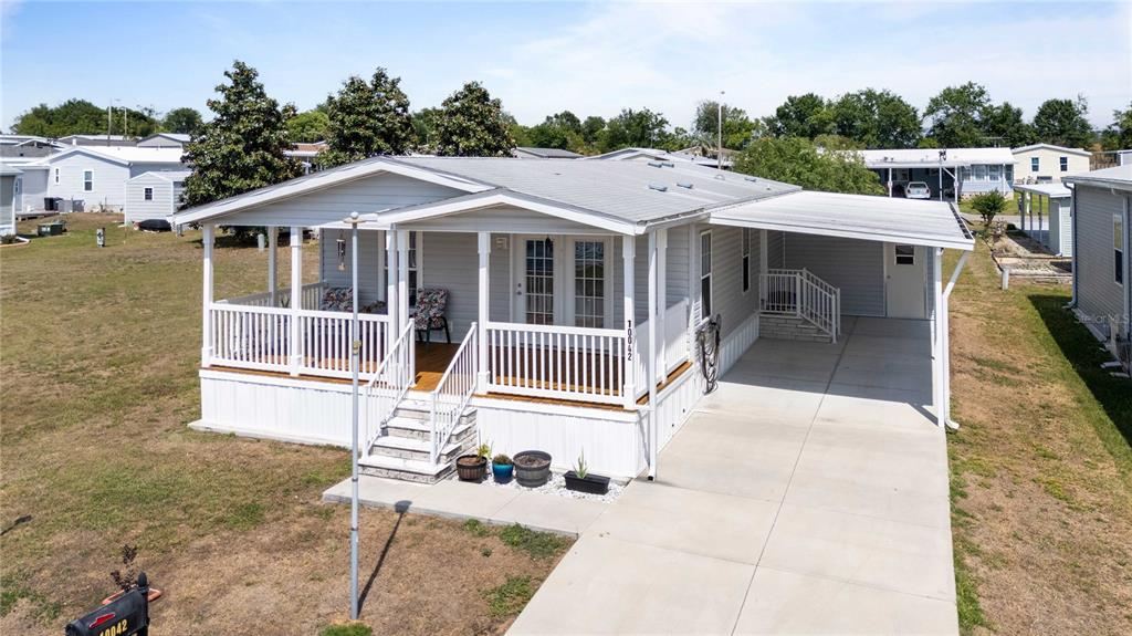 A light gray manufactured home features a front porch, a carport, and a concrete driveway — 10042 COLLINGWOOD AVENUE, DADE CITY, FL