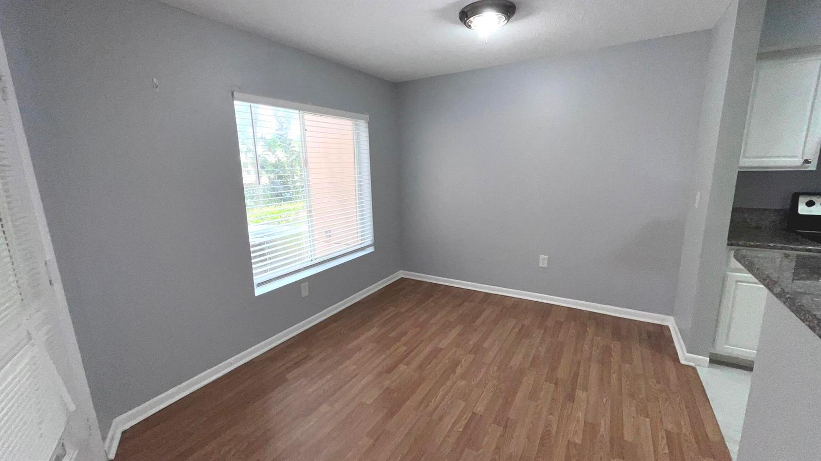 An empty dining area features gray walls, wood-look flooring, and a window with blinds — 815 W Boynton Beach Boulevard # 107, Boynton Beach FL 33426, BOYNTON BEACH, FL