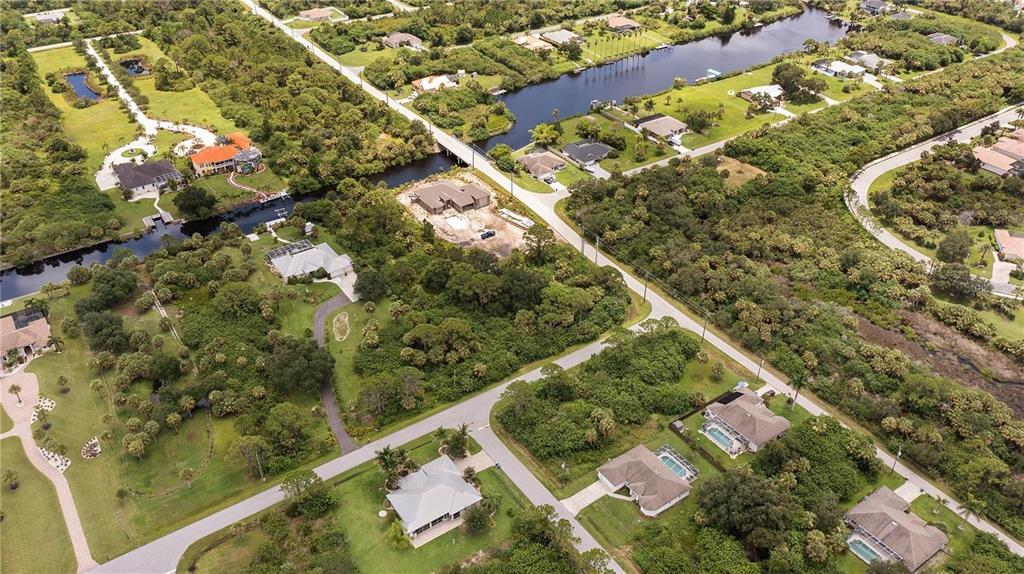An aerial view shows several houses, a canal, and dense vegetation in a suburban neighborhood — 1510 CARSWELL STREET, PORT CHARLOTTE, FL