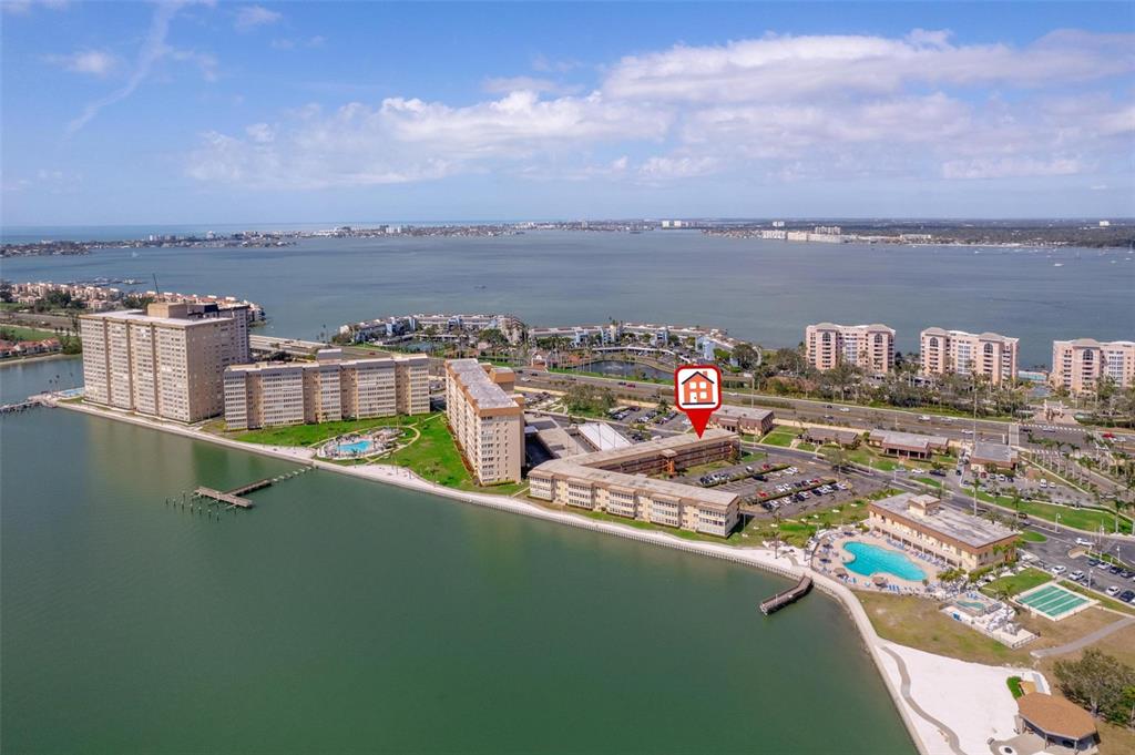 An aerial view shows a waterfront apartment complex with multiple buildings, pools, and parking lots — 5020 BRITTANY DRIVE S UNIT 324, ST PETERSBURG, FL
