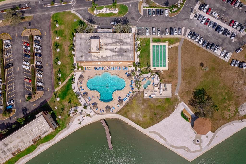 An aerial view shows a community clubhouse with a pool, parking lots, and a lake — 5020 BRITTANY DRIVE S UNIT 324, ST PETERSBURG, FL