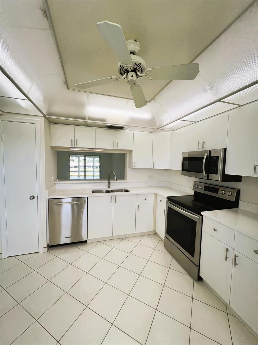 A kitchen with white cabinets, stainless steel appliances, white countertops, and a ceiling fan — 3303 Aruba Way # 4, Coconut Creek FL 33066, COCONUT CREEK, FL