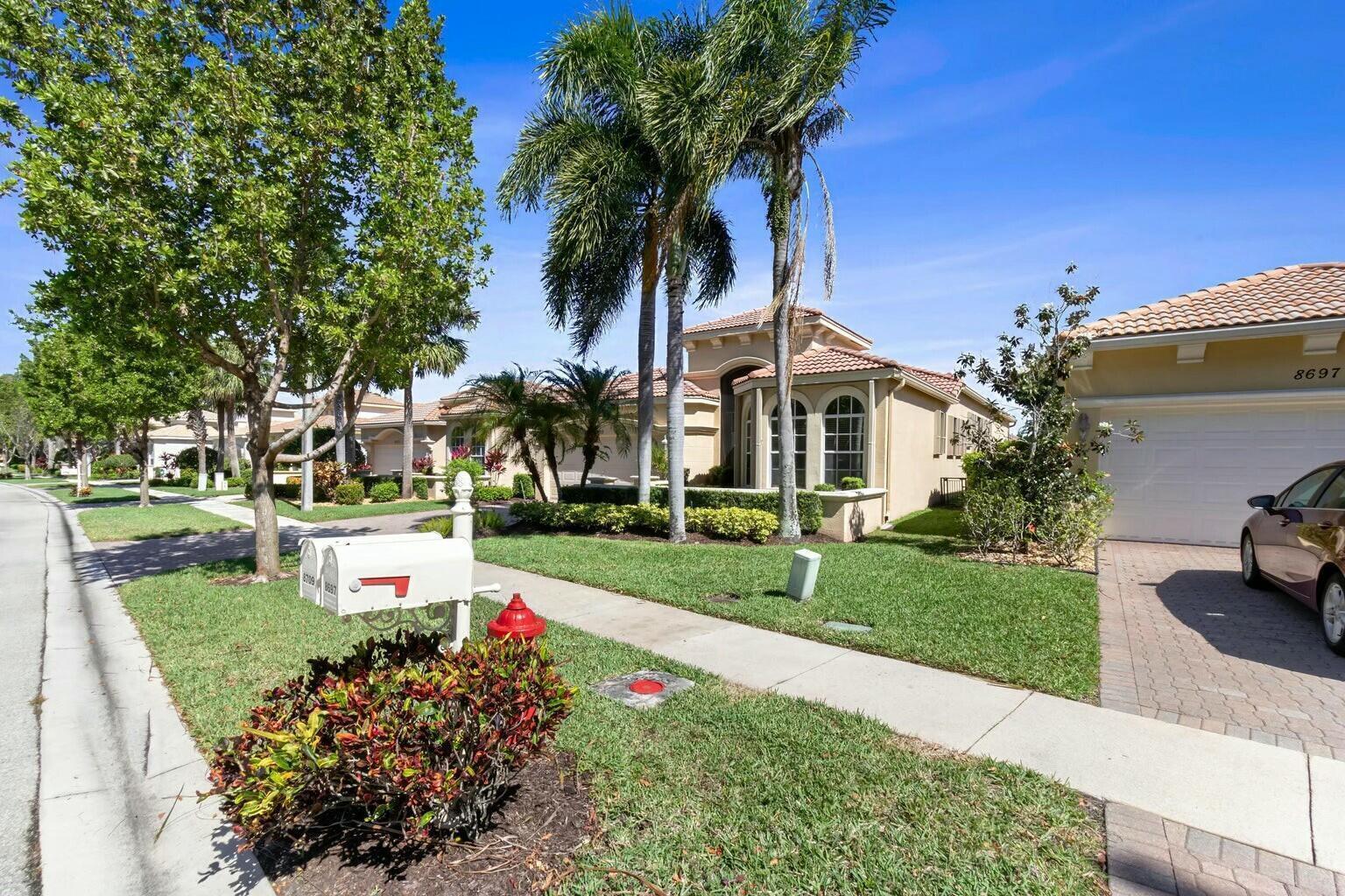 A suburban house exterior features a tiled roof, palm trees, and a paved driveway — 8709 Via Grande E, Wellington FL 33411, WELLINGTON, FL