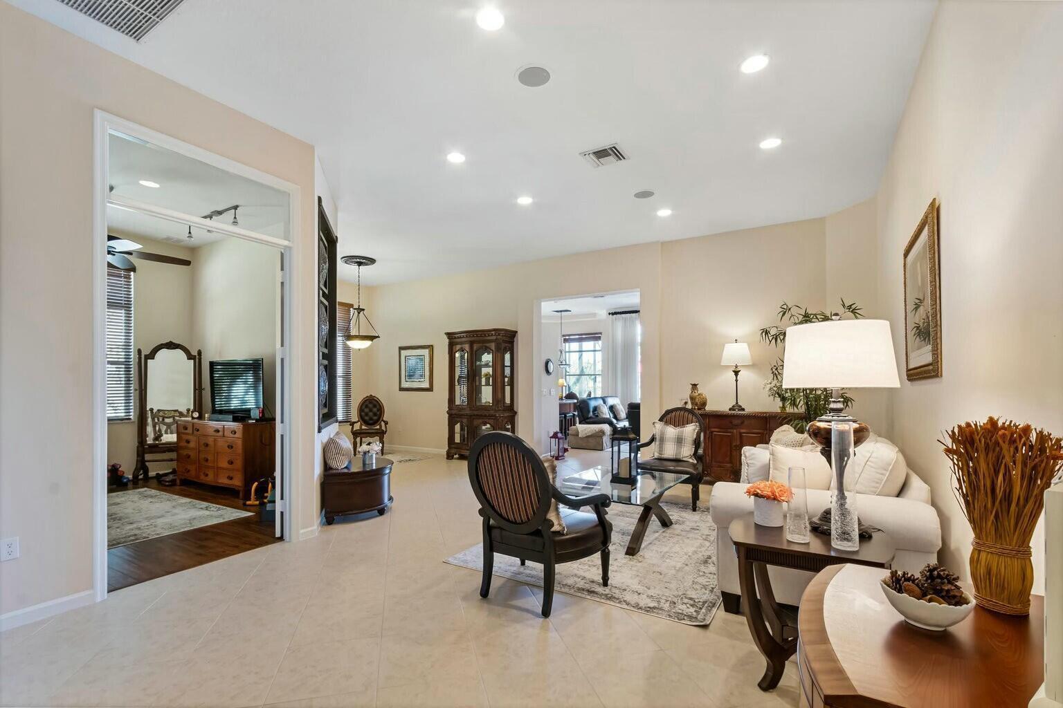 A living room features tile flooring, recessed lighting, and a view into an adjacent room — 8709 Via Grande E, Wellington FL 33411, WELLINGTON, FL