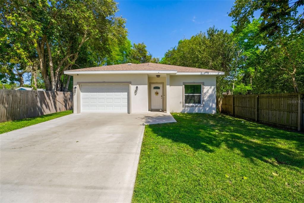 A single-story house with a white garage, a front door, and a concrete driveway — 637 HOLMES AVENUE, DAYTONA BEACH, FL