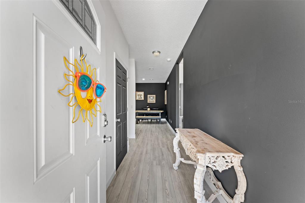 A hallway with light wood flooring, a dark accent wall, and a decorative console table — 637 HOLMES AVENUE, DAYTONA BEACH, FL