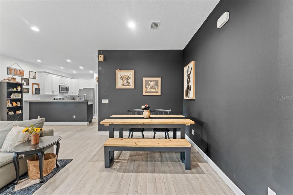 A dining area with a wooden table and bench sits against a dark accent wall — 637 HOLMES AVENUE, DAYTONA BEACH, FL