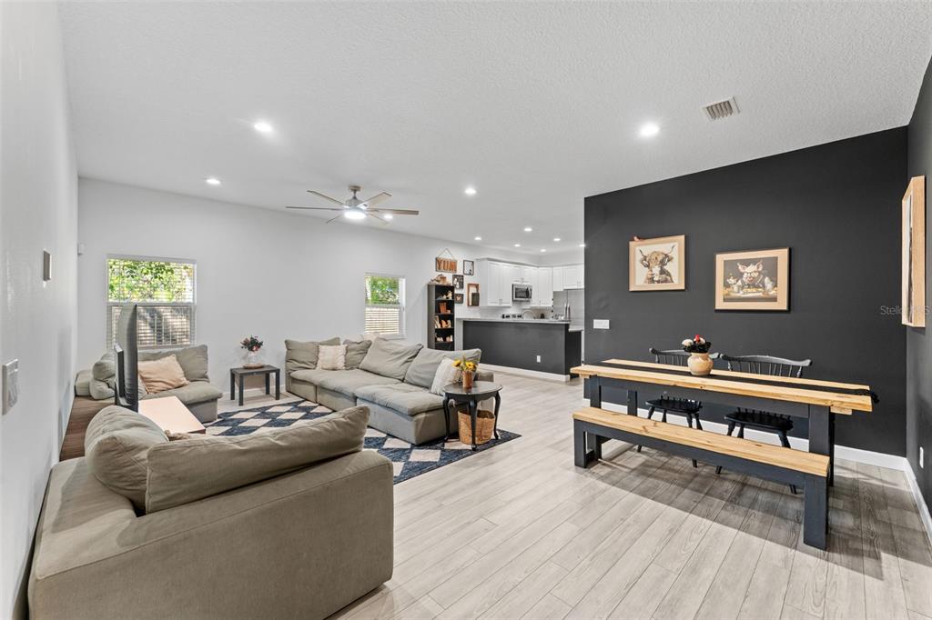 An open-concept living and dining area features light wood-look flooring and a dark accent wall — 637 HOLMES AVENUE, DAYTONA BEACH, FL