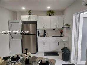 A small kitchen features white cabinets, stainless steel appliances, and a stacked washer and dryer — 1130 NE 201st Ter # B, Miami FL 33179, MIAMI, FL