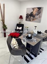 A dining area features a small table with two chairs, a black armchair, and wall art — 1130 NE 201st Ter # B, Miami FL 33179, MIAMI, FL