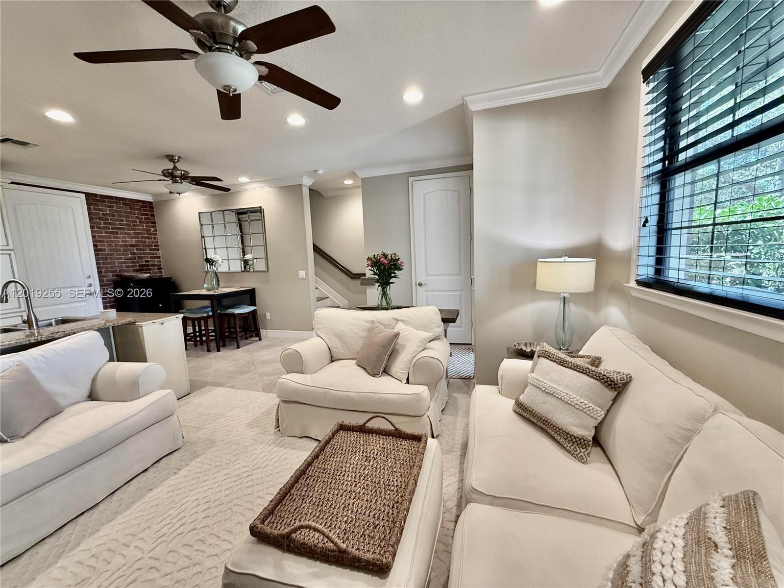 A living room features white sofas, a brick accent wall, and a ceiling fan — 867 S Ocean Blvd, Pompano Beach FL 33062, POMPANO BEACH, FL