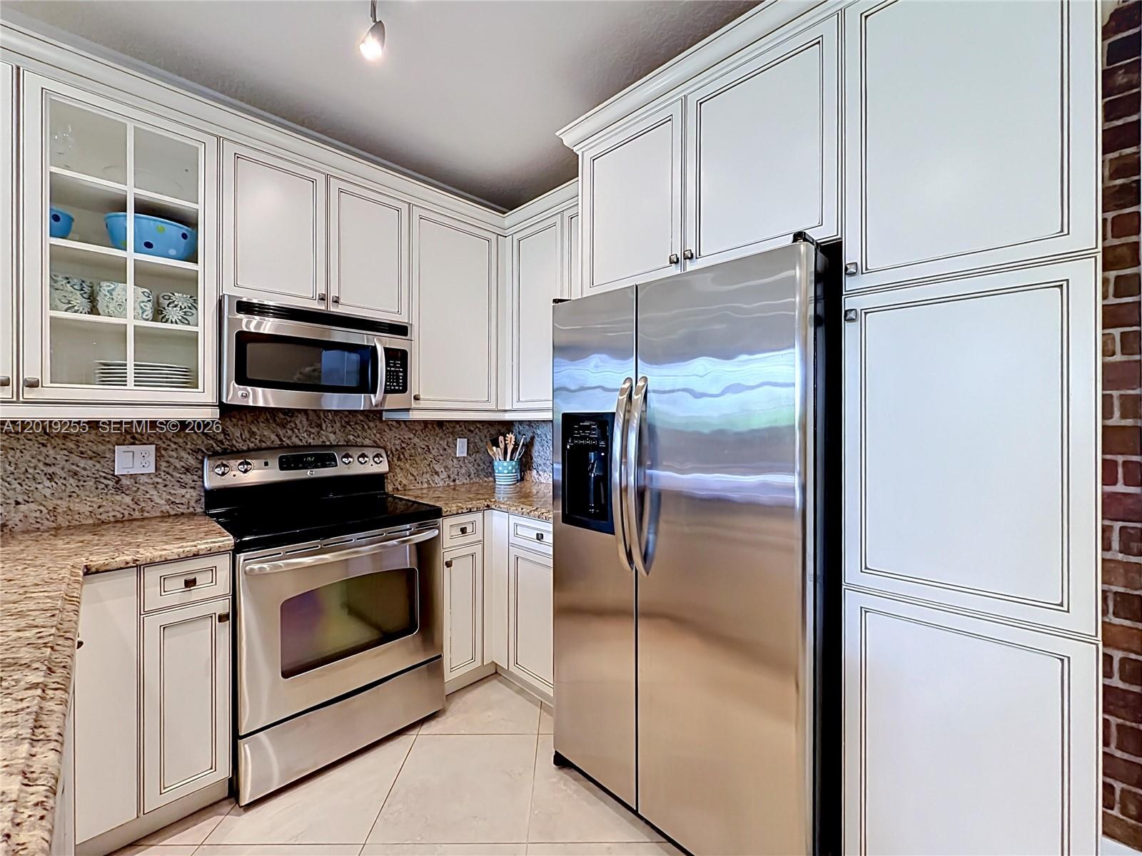 A kitchen features white cabinets with dark trim, stainless steel appliances, and granite countertops — 867 S Ocean Blvd, Pompano Beach FL 33062, POMPANO BEACH, FL