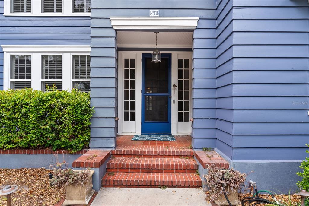The exterior of a blue house features a brick stoop and a blue front door — 418 JASMINE WAY, CLEARWATER, FL