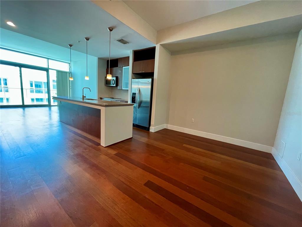 A modern kitchen features a breakfast bar, stainless steel appliances, and hardwood flooring — 111 N 12TH STREET UNIT 1810, TAMPA, FL