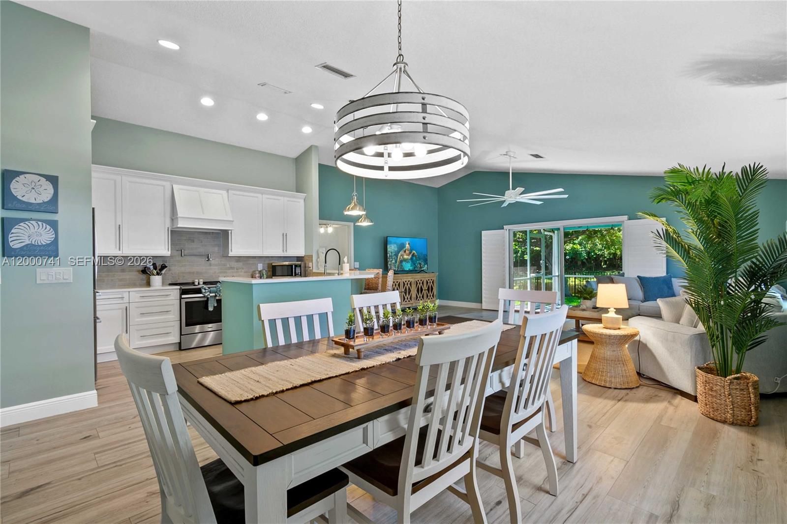 A dining area with a wooden table and chairs sits before an open-concept kitchen — 104 Old Jupiter Beach Road, Jupiter FL 33477, JUPITER, FL
