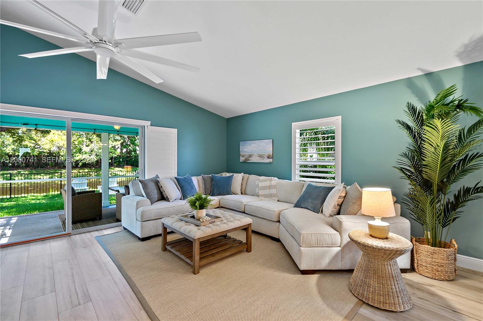 A living room features a large sectional sofa, teal walls, and a sliding glass door — 104 Old Jupiter Beach Road, Jupiter FL 33477, JUPITER, FL