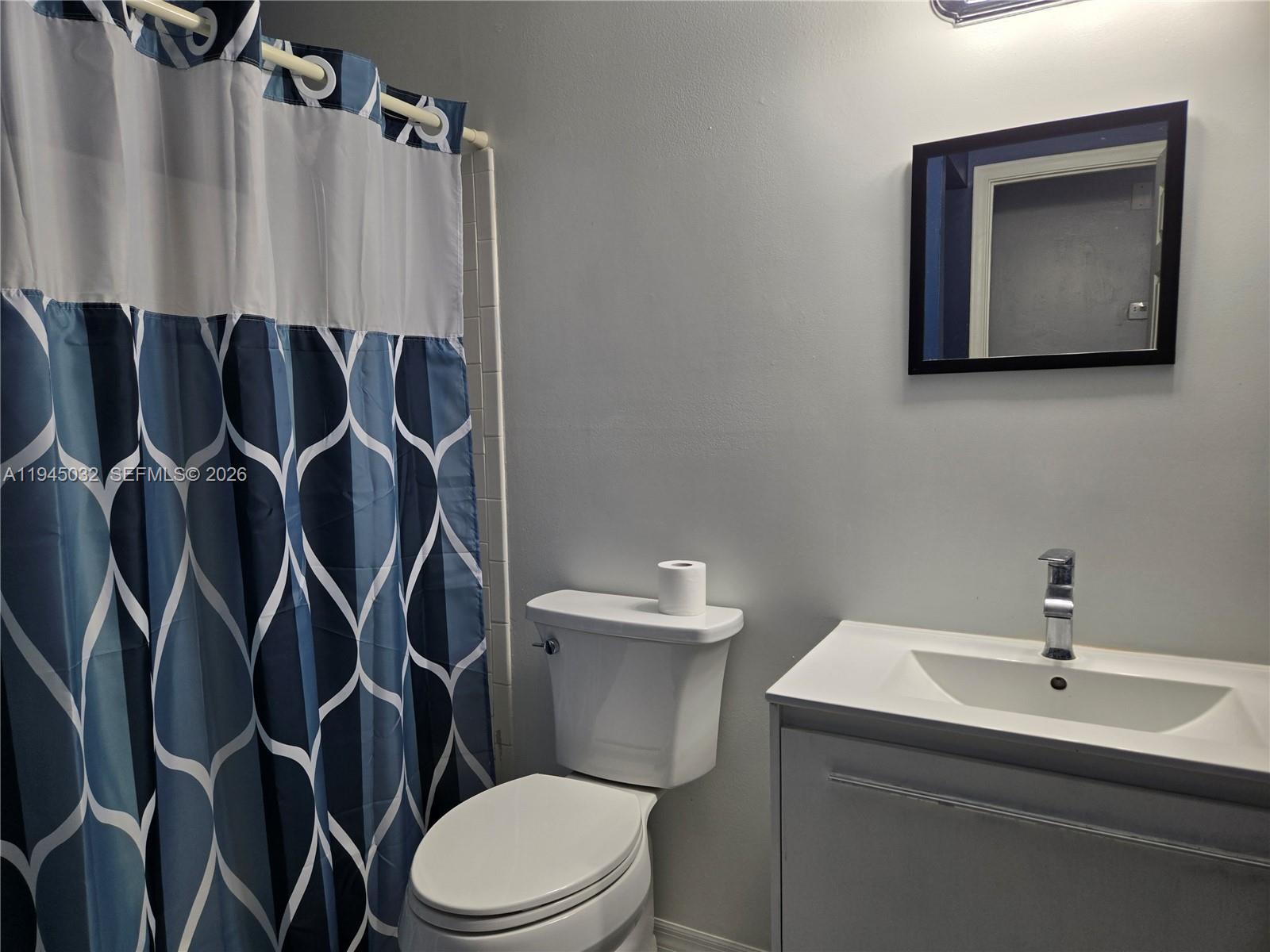 A bathroom features a blue patterned shower curtain, a white toilet, and a vanity sink — 842 Banks Rd, Coconut Creek FL 33063, COCONUT CREEK, FL