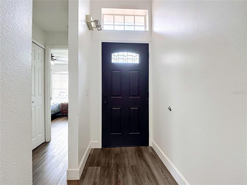 An entryway features a dark front door, wood-look flooring, and a transom window above — 2469 HYBRID DRIVE, KISSIMMEE, FL
