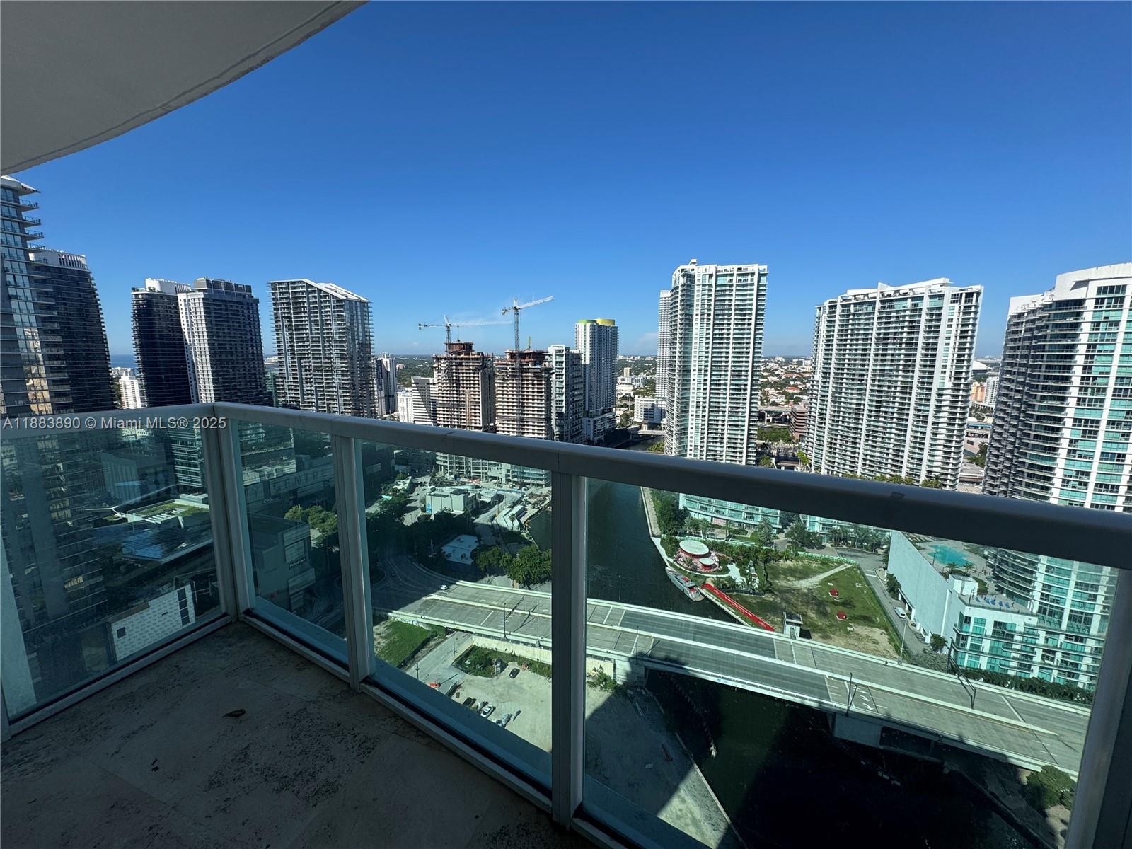 A high-rise balcony overlooks a city skyline with multiple skyscrapers, a river, and a bridge — 31 SE 5th St # 3817, Miami FL 33131, MIAMI, FL