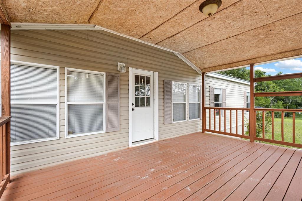 A covered wooden deck with a railing sits in front of a tan-sided mobile home — 4689 NW 26TH STREET, BELL, FL
