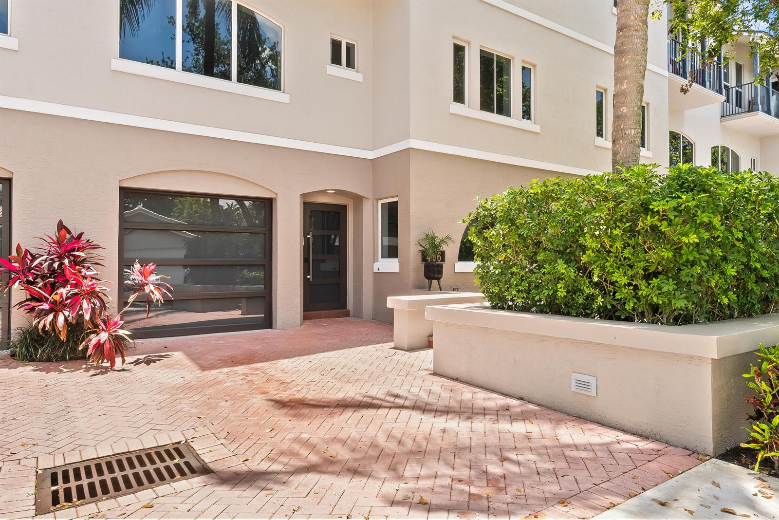 The exterior of a beige townhouse features a brick driveway, a garage, and a front door — 456 E Boca Raton Road, Boca Raton FL 33432, BOCA RATON, FL
