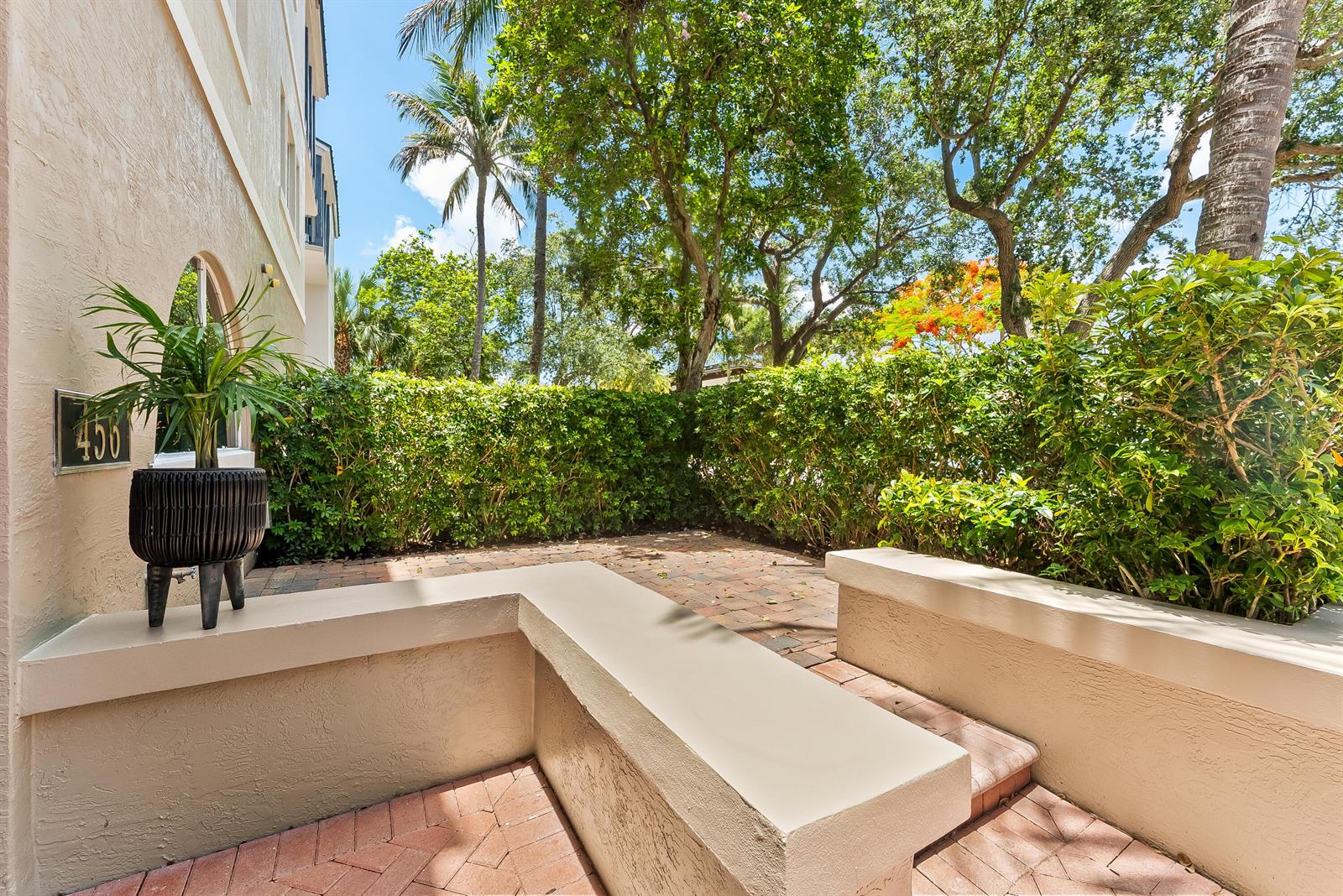 A paved patio area features built-in concrete benches and a potted plant against a hedge — 456 E Boca Raton Road, Boca Raton FL 33432, BOCA RATON, FL