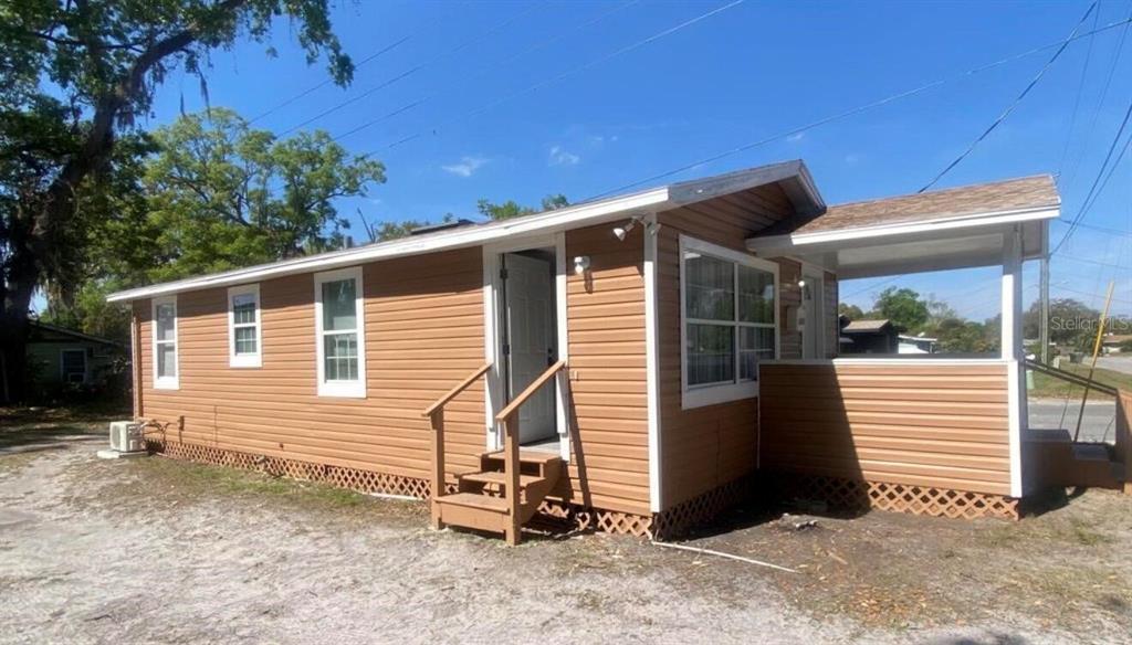 A tan, single-story house with horizontal siding, a small front porch, and wooden stairs — 1810 N BRACK STREET, KISSIMMEE, FL