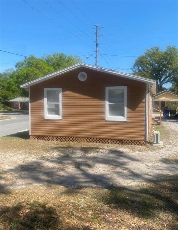 The exterior of a small, tan-sided house features two windows and a lattice foundation skirt — 1810 N BRACK STREET, KISSIMMEE, FL