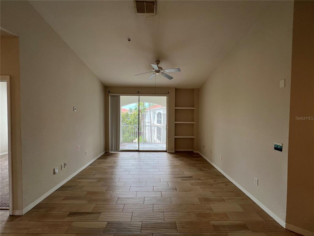 An empty living room features wood-look tile flooring, a ceiling fan, and built-in wall shelves — 2537 MAITLAND CROSSING WAY UNIT 308, ORLANDO, FL