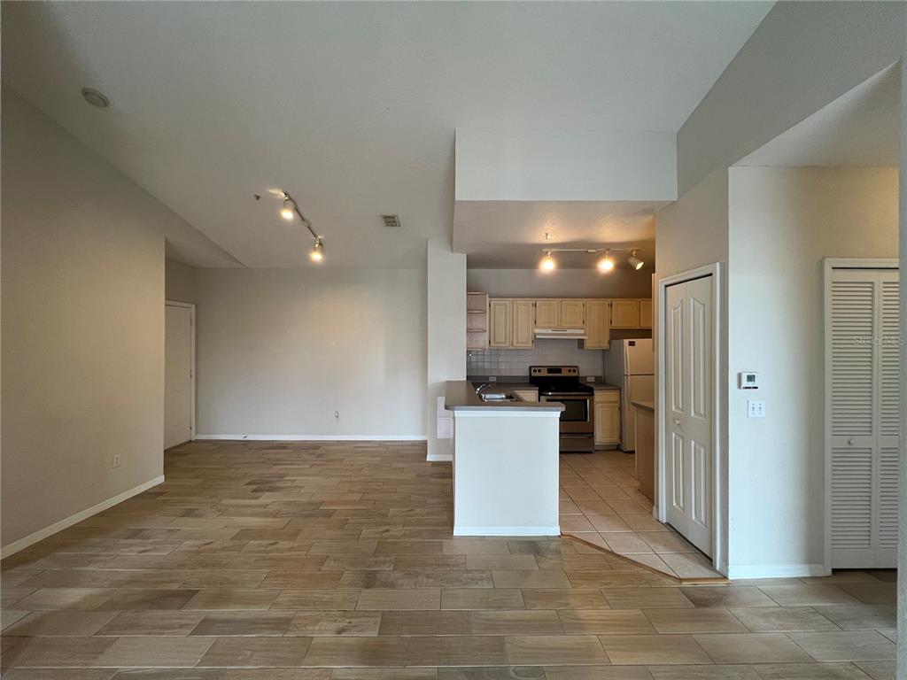 An open-concept living area features wood-look tile flooring and a kitchen with light wood cabinets — 2537 MAITLAND CROSSING WAY UNIT 308, ORLANDO, FL