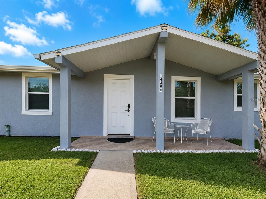 A gray house exterior features a covered front porch with a white door and chairs — 14490 SW 41ST AVENUE ROAD, OCALA, FL