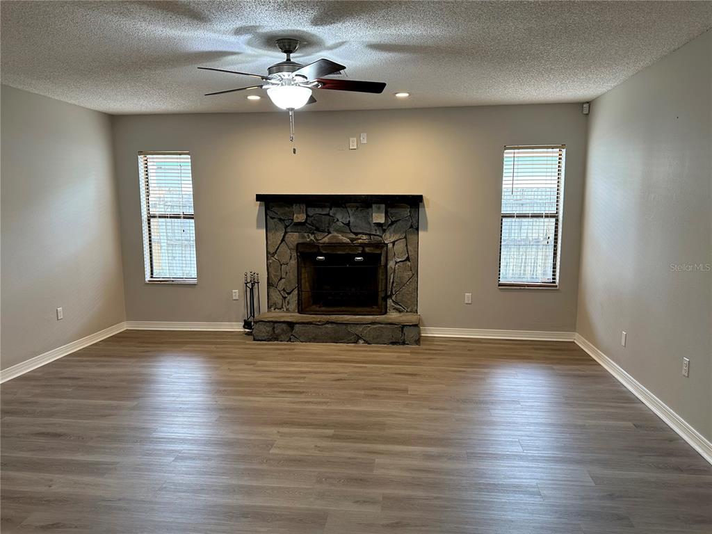 A living room features light wood-look flooring, gray walls, and a stone fireplace — 2013 KAMENSKY ROAD, CLEARWATER, FL