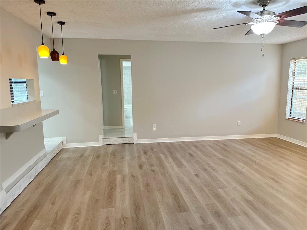 A living room with light wood-look flooring, a ceiling fan, and a pass-through kitchen counter — 2013 KAMENSKY ROAD, CLEARWATER, FL